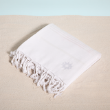 Joie de Vivre keyf Turkish beach towel folded with logo on sand