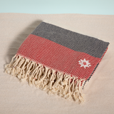 Anchors Away keyf Turkish beach towel folded with logo on sand