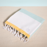 La Dolce Vita keyf Turkish beach towel folded with logo on sand